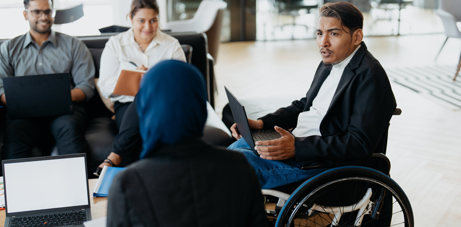 An Asian disabled businessman on wheelchair explaining business plans to his team during a meeting