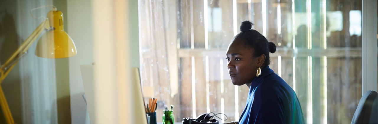 A woman looks at several screens while working from home.
