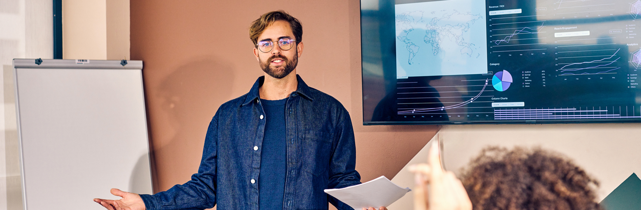Caucasian male presenting data analysis on a screen in a conference room. Professional presentation and strategic planning concept