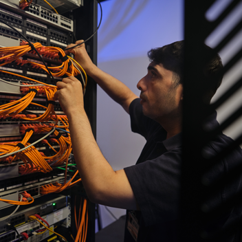 Technician checking cables in a rack mounted server.