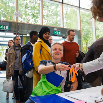 Smiling woman in wheelchair arriving and checking in at conference registration table