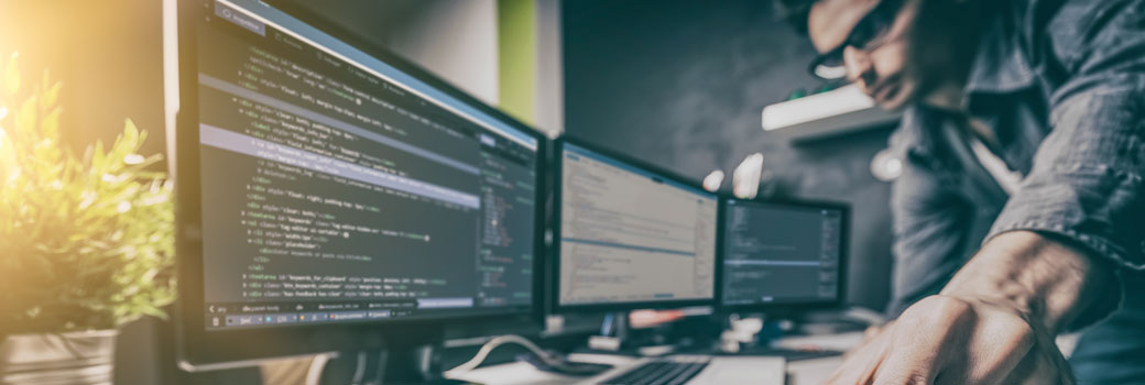 Man looking at code on screens.