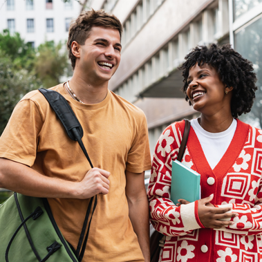 Two university students laughing while walking on campus.