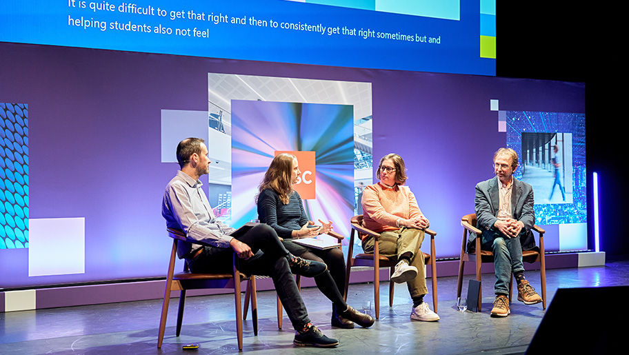 A panel of four speakers sitting on a stage.