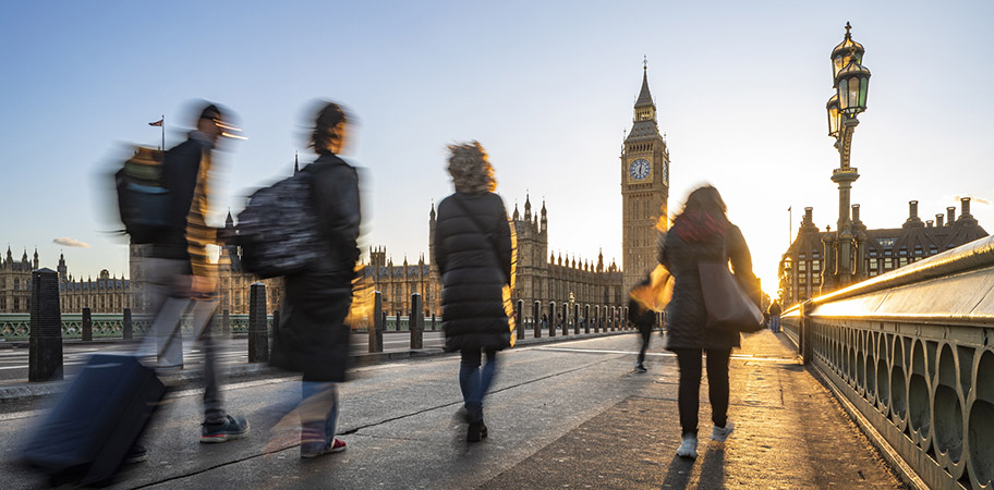 A group of people walking across a bridge in London.
