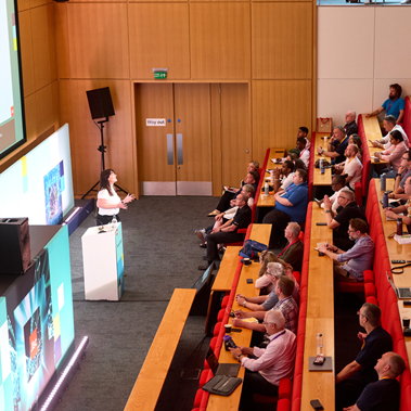 A presenter giving a talk to an audience at Networkshop 2026