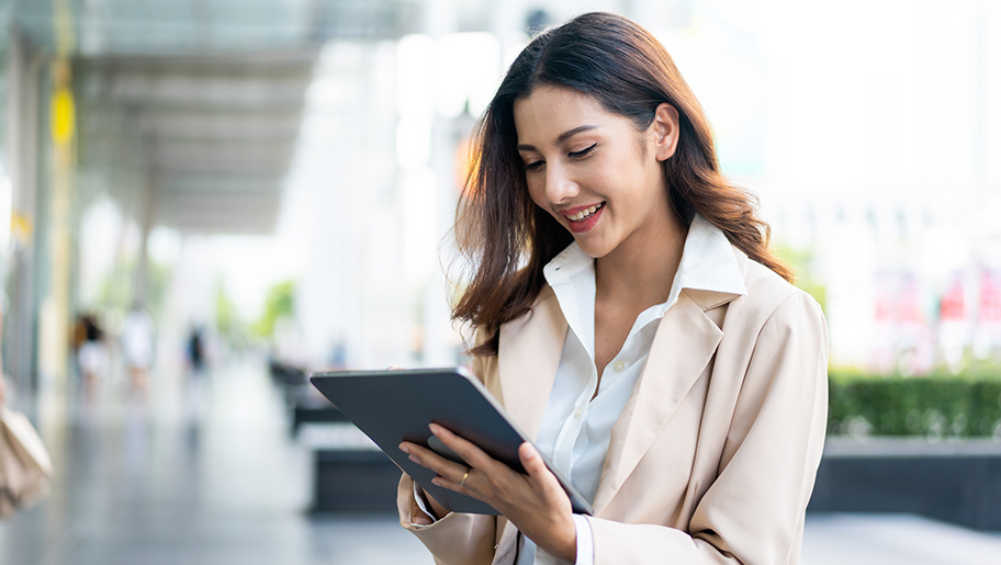 A smiling woman looking at a tablet.