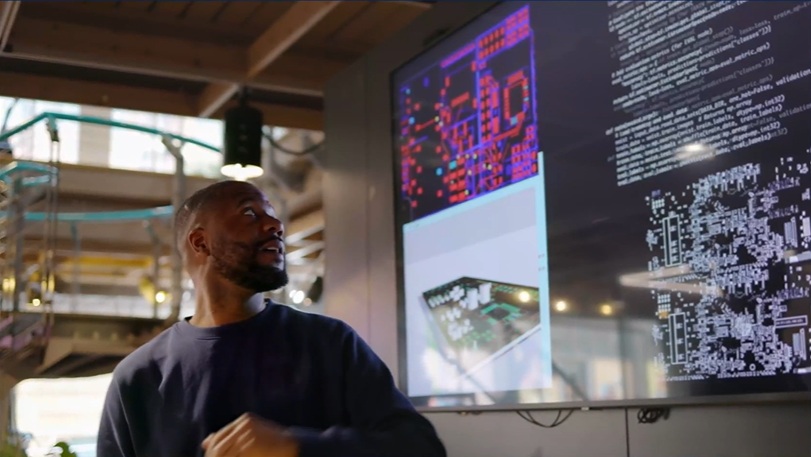 A male tutor looking at a large wall mounted screen.