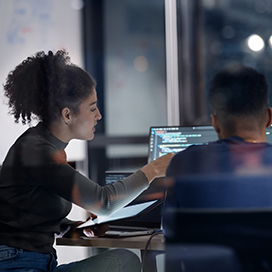 Two work colleagues working together at a computer screen.