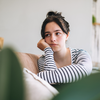 Upset teenage girl looking away and sitting in room at home