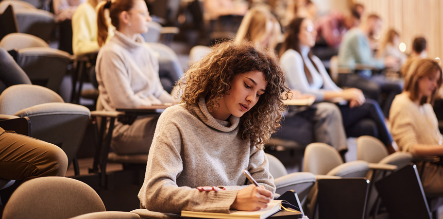 College student writing an exam during a class at lecture hall.