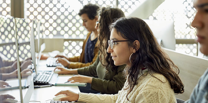 Students sitting at a table with computers